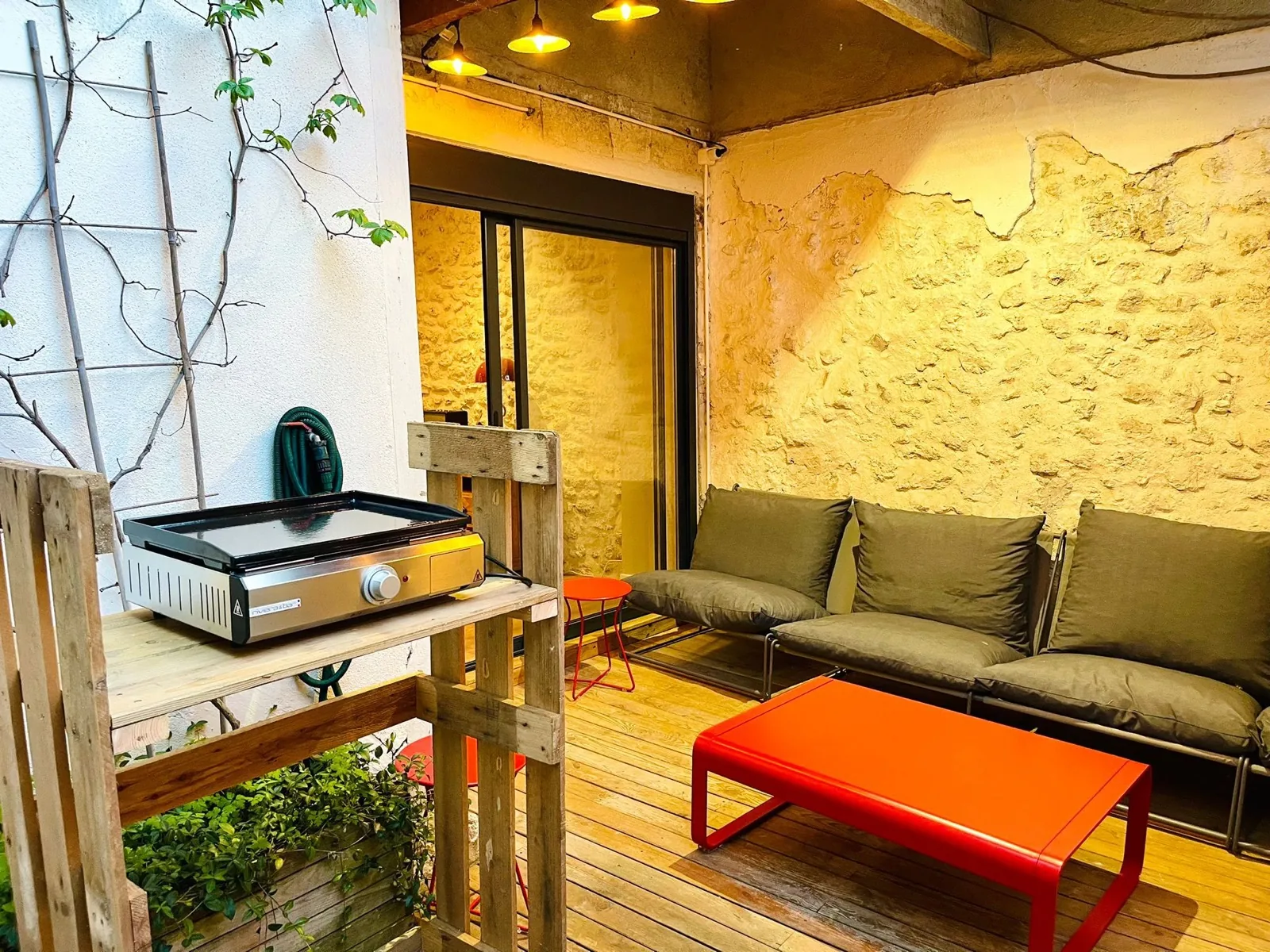 Terrasse intérieure en bois avec plancha et guirlande lumineuse — Loire Retreat